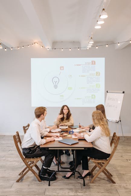 Group of professionals discussing business strategy with a projector and notepad.